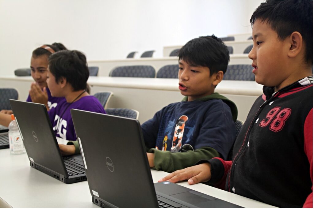 Four students discuss a project while working on Dell laptops.