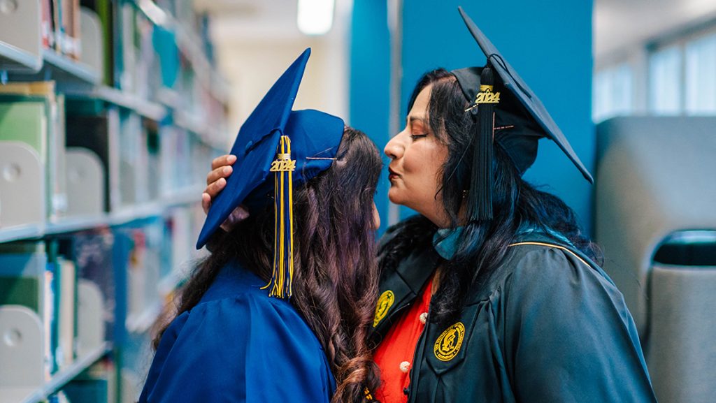 Dr. Qindeel, student in IPiE's MST2 program, kisses the forehead of her daughter on the day of their graduation.